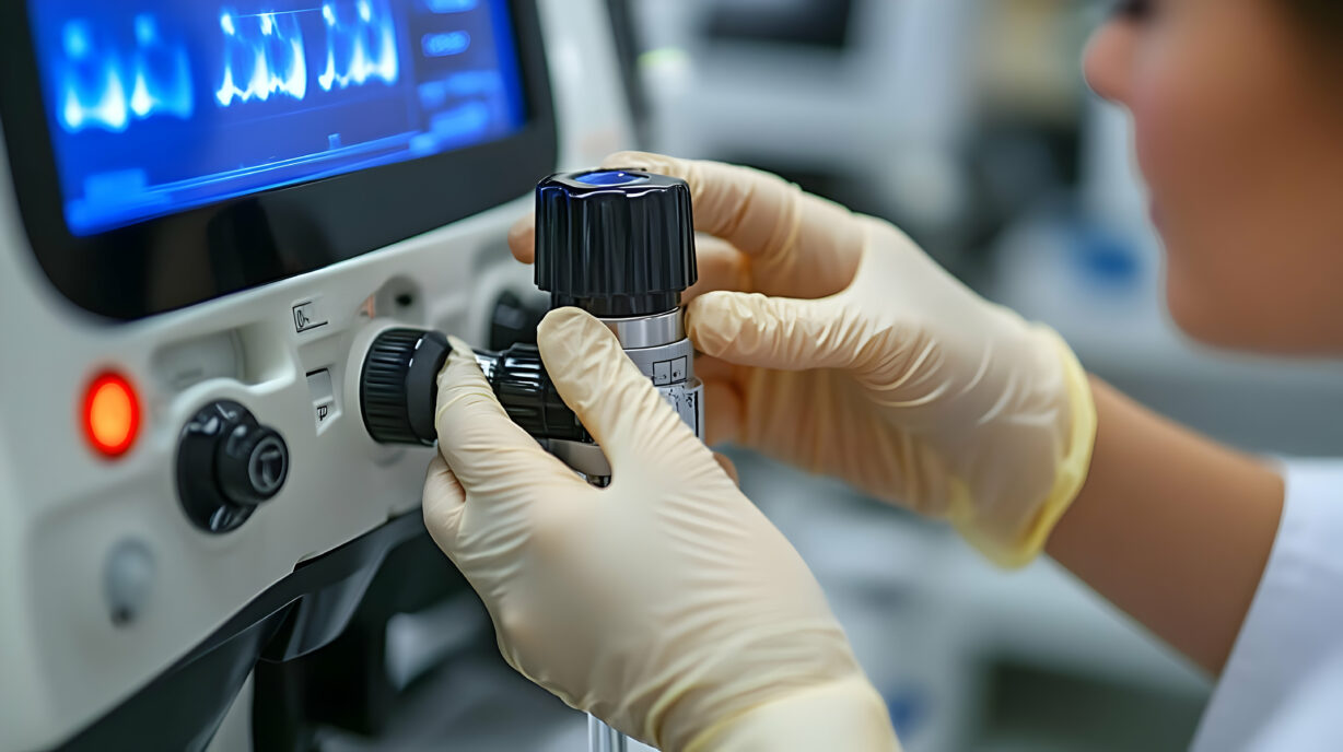 A person adjusting a medical device in a clinical setting.