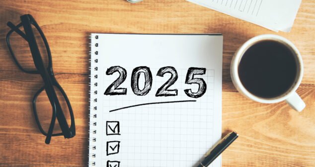 Medical Device Resolutions This image features a notepad with "2025" written boldly at the top, accompanied by a checklist containing three checked boxes. Nearby, there is a pair of eyeglasses, a cup of coffee, a pen, and a calculator, all arranged on a wooden table.