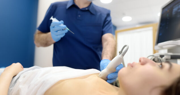 Mammalogist doctor examines a woman breasts and lymph nodes during appointment. Skillful oncologist puncture of mammary glands of young patient under review ultrasound for diagnosis of breast cancer.