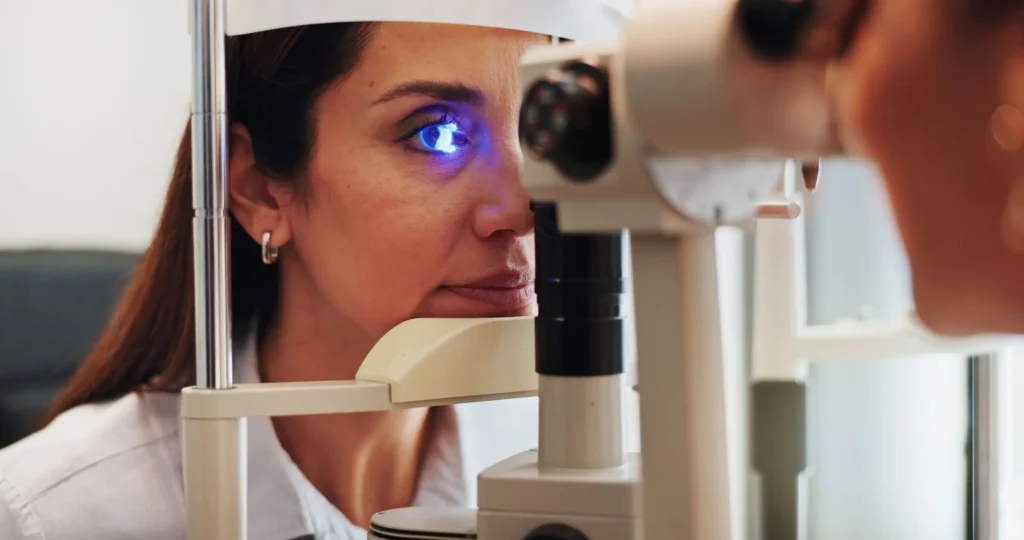 Patient undergoing optical eye imaging exam using a slit lamp style diagnostic device for detailed corneal and anterior eye analysis.