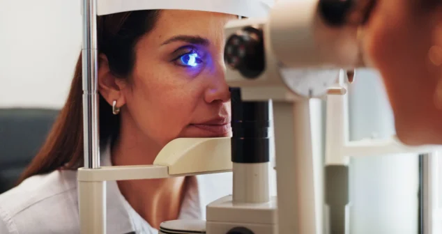 Patient undergoing optical eye imaging exam using a slit lamp style diagnostic device for detailed corneal and anterior eye analysis.