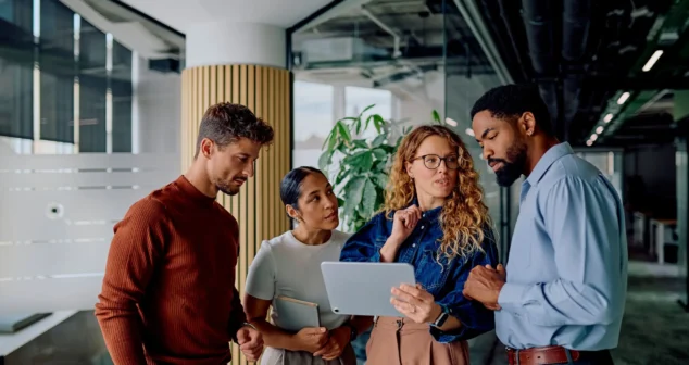 Cross-functional MedTech team discussing requirements on a tablet during a medical device development meeting.