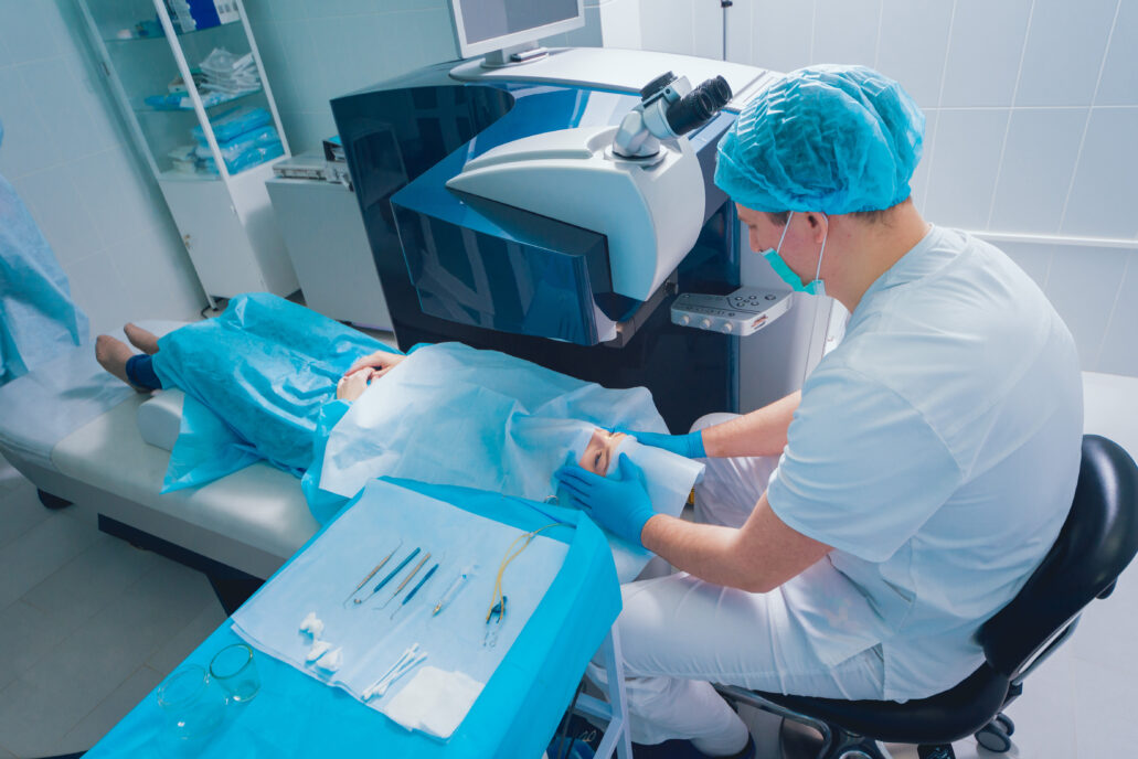 Laser vision correction. A patient and team of surgeons in the operating room during ophthalmic surgery. Eyelid speculum. Lasik treatment. Patient under sterile cover