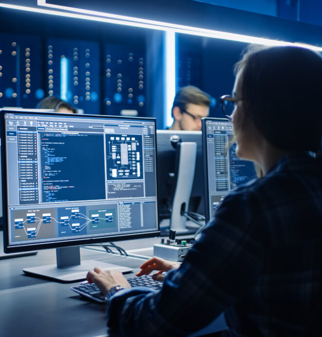 Female IT Programmer Working on Desktop Computer in Data Center System Control Room. Team of Young Professionals Doing Code Programming