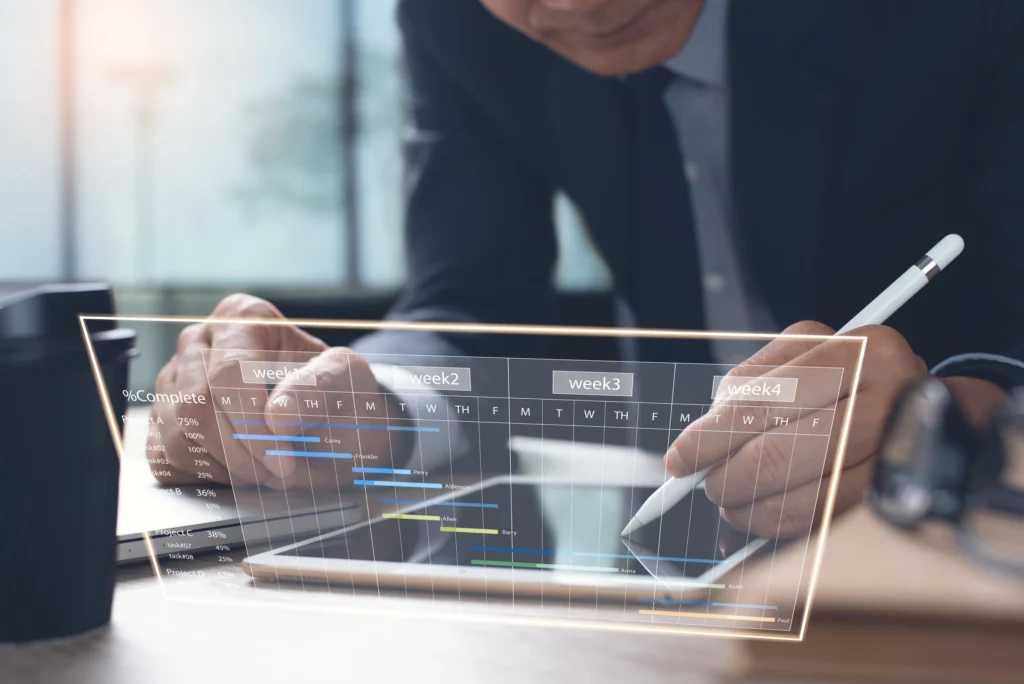 Project manager using digital tablet to update cloud-based Gantt chart for medical device development planning.