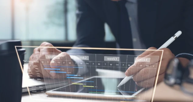 Project manager using digital tablet to update cloud-based Gantt chart for medical device development planning.
