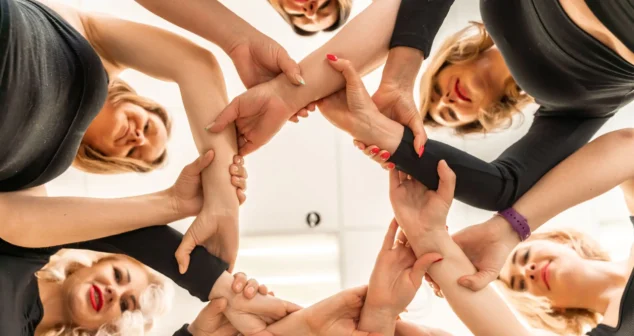 Team of people holding hands. Group of happy young women holding hands. Bottom view, low angle shot of human hands. Friendship and unity concept