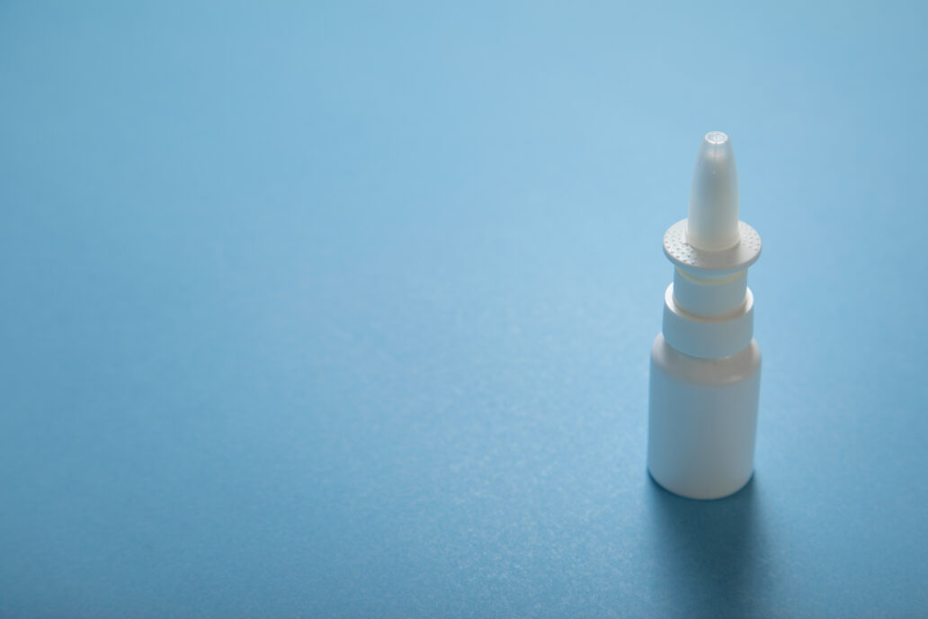 White nose spray bottle on the blue background.