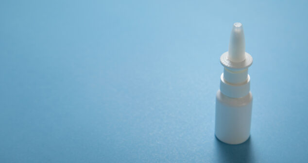 White nose spray bottle on the blue background.