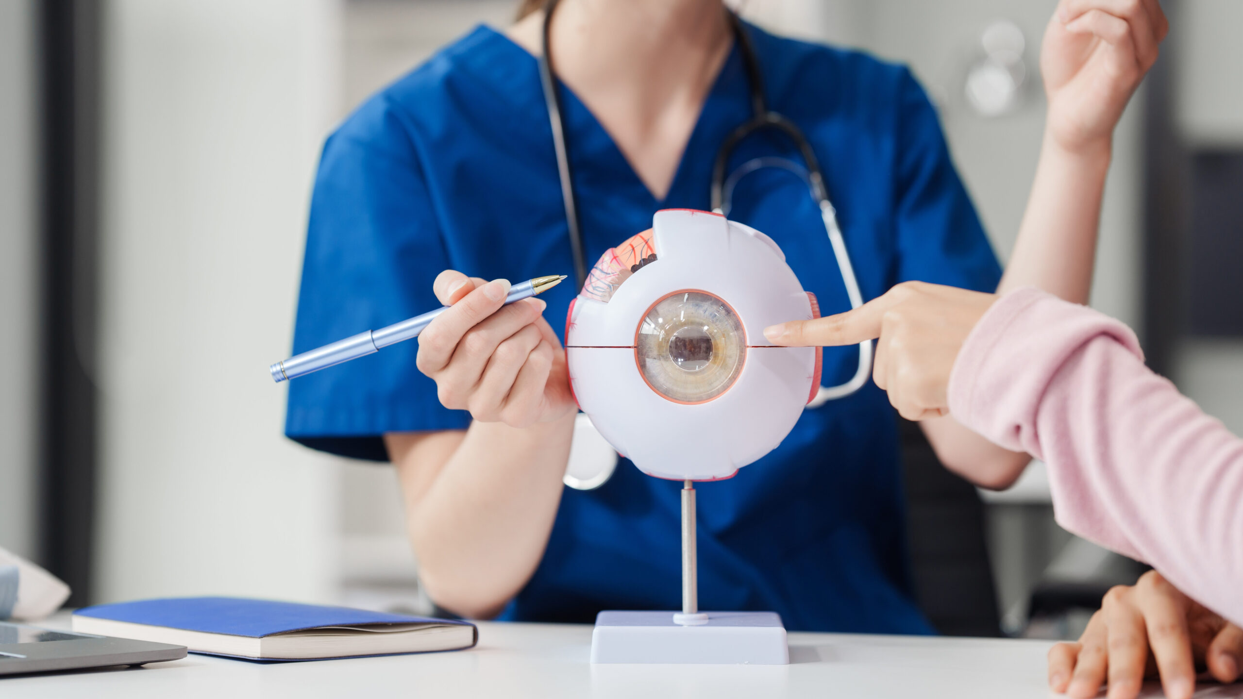 Therapy Devices Female Caucasian ophthalmologist explains about eye diseases using the eye model with an Asian female patient At the table in the hospital examination room, Glaucoma, Cataract, Diabetic Retinopathy