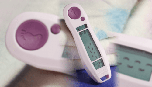 Handheld Baby Movement Tracker device positioned next to a baby bottle, highlighting its compact design and display screen.