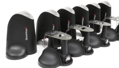 Row of black IVD cartridge test fixtures arranged on a bench with metal arms and mounting plates for repeated testing cycles.