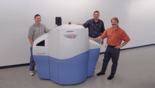 Team members standing beside a full-scale non-functional mock-up of the Gamma Medica multi-modality imaging device.