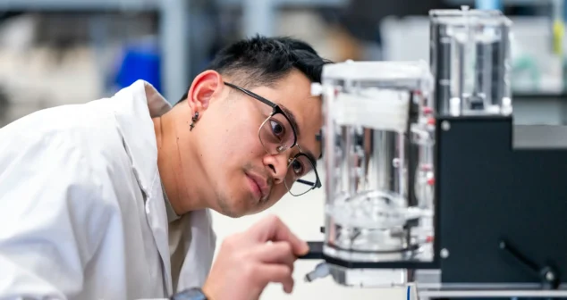 Lab technician in Victoria office inspecting a transparent medical device prototype.
