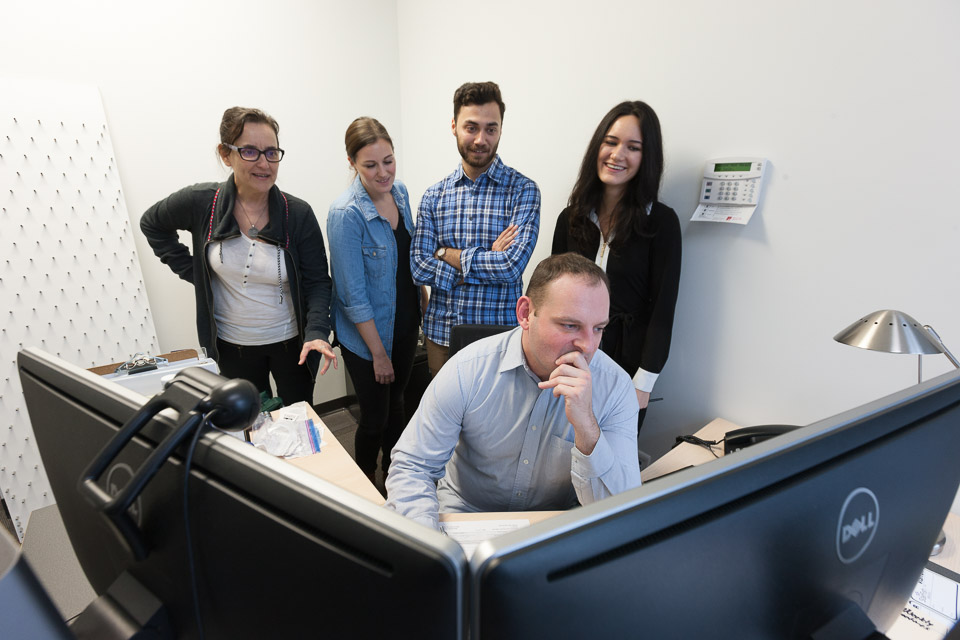 device product development

Accessibility: man pondering a double screen computer with four people looking from behind him.