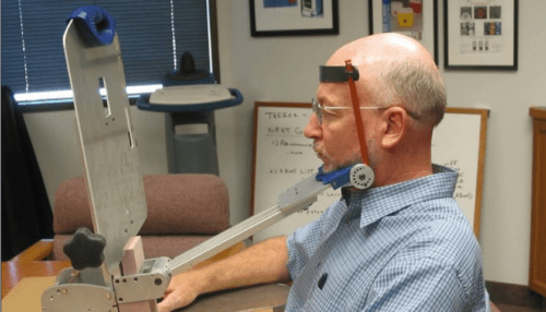 Man sitting in front of the Vision Restoration Therapy device wearing a headband sensor while completing a visual stimulation therapy session.