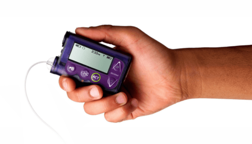 Person holding a MiniMed insulin pump in one hand, showing scale, interface screen and control buttons.