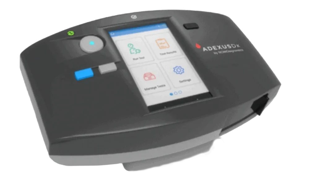 Close-up view of the ADEXUSDx point-of-care analyzer showing the touchscreen interface and device controls.