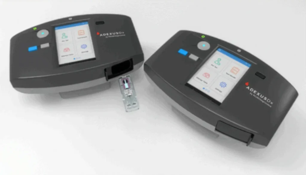 Two ADEXUSDx analyzers with one device displaying an inserted test cassette for point-of-care diagnostics.