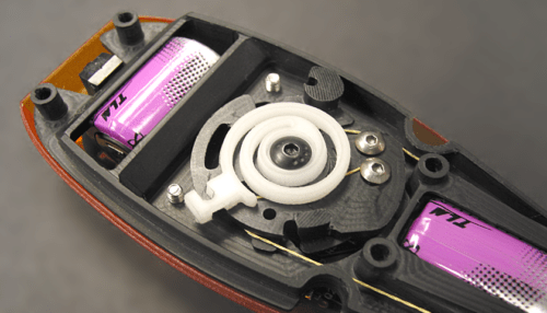 Close-up view of the ocular implant tool’s internal mechanical components including gears, springs and housing details.