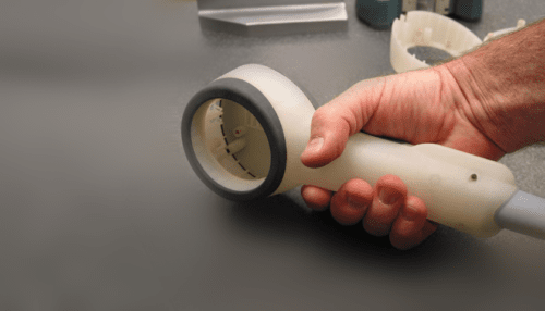 Clinician holding the PhotoThera NeuroThera handpiece against a patient’s shaved scalp during near-infrared therapy positioning.