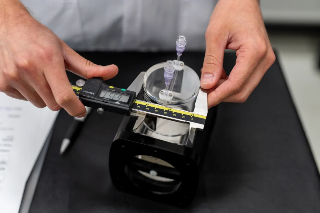 Technician using digital calipers to validate component dimensions during medical device testing.