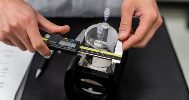 Technician using digital calipers to validate component dimensions during medical device testing.
