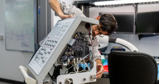 One engineer works hands-on with this board's internals, carrying it from design through bring-up