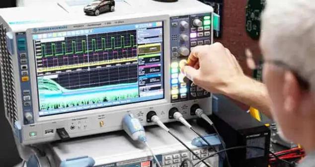 Technician adjusting oscilloscope readings during electronic device testing.