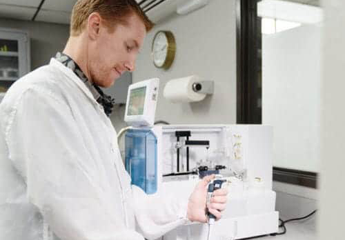 Medical device engineer in a lab using pipette equipment for testing.