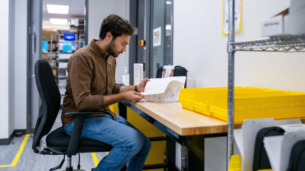 Engineer reviewing printed documentation at a workbench before signing a medical device development contract
