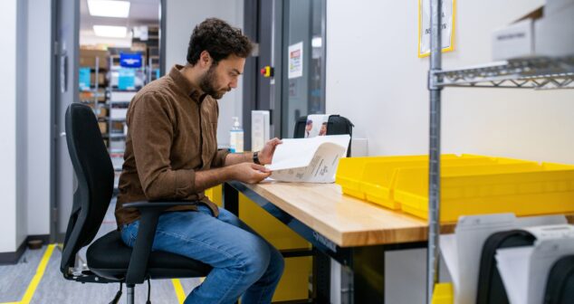 Engineer reviewing printed documentation at a workbench before signing a medical device development contract