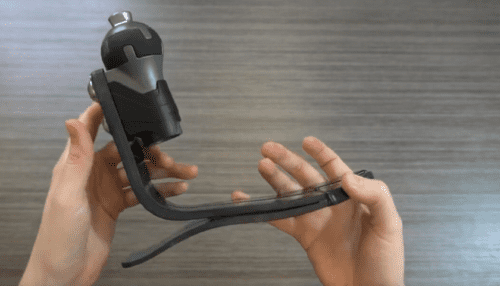 Person holding a ShockWave prosthetic foot showing the curved carbon fiber blade and integrated spherical shock absorber.