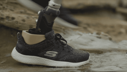 A ShockWave prosthetic foot with spherical shock unit attached to a sneaker during a step on an outdoor surface.