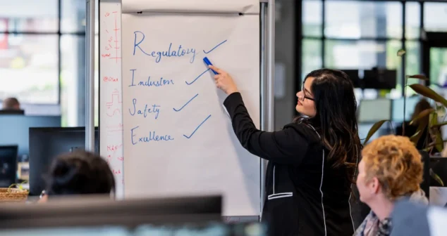 Team leader presenting regulatory, inclusion, safety, and excellence values on a flip chart in the Victoria office.