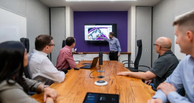 Design review meeting in the Victoria office with engineers gathered around a presentation screen.
