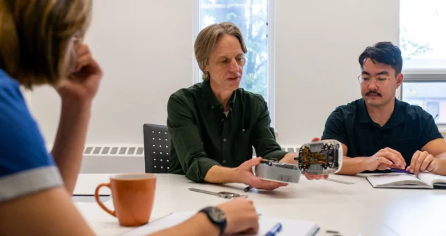 Medical device engineering firm team walks a client through an opened prototype and its circuit board