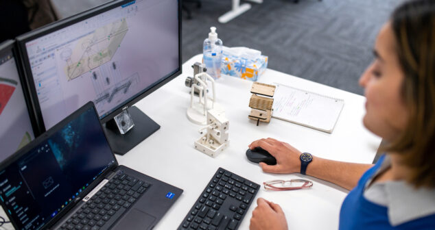 Transfer to Manufacturing Accessibility: Woman sitting at desk viewing screen and clicking on her mouse