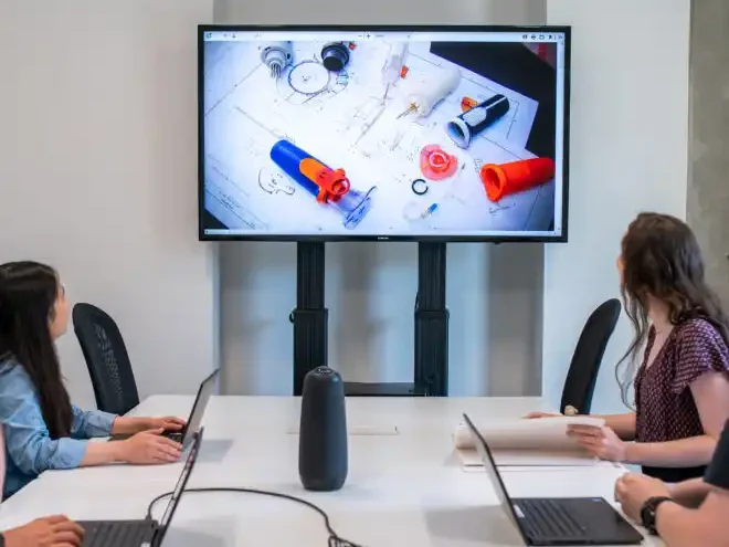 Medical Device Product Engineering Services Image of engineers sitting at table reviewing medial device on large screen TV