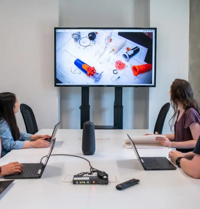 Medical Device Product Engineering Services Image of engineers sitting at table reviewing medial device on large screen TV