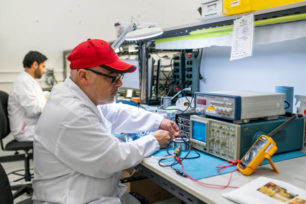 Accessibiity: Two assembly workers putting together units on manufacturing floor.