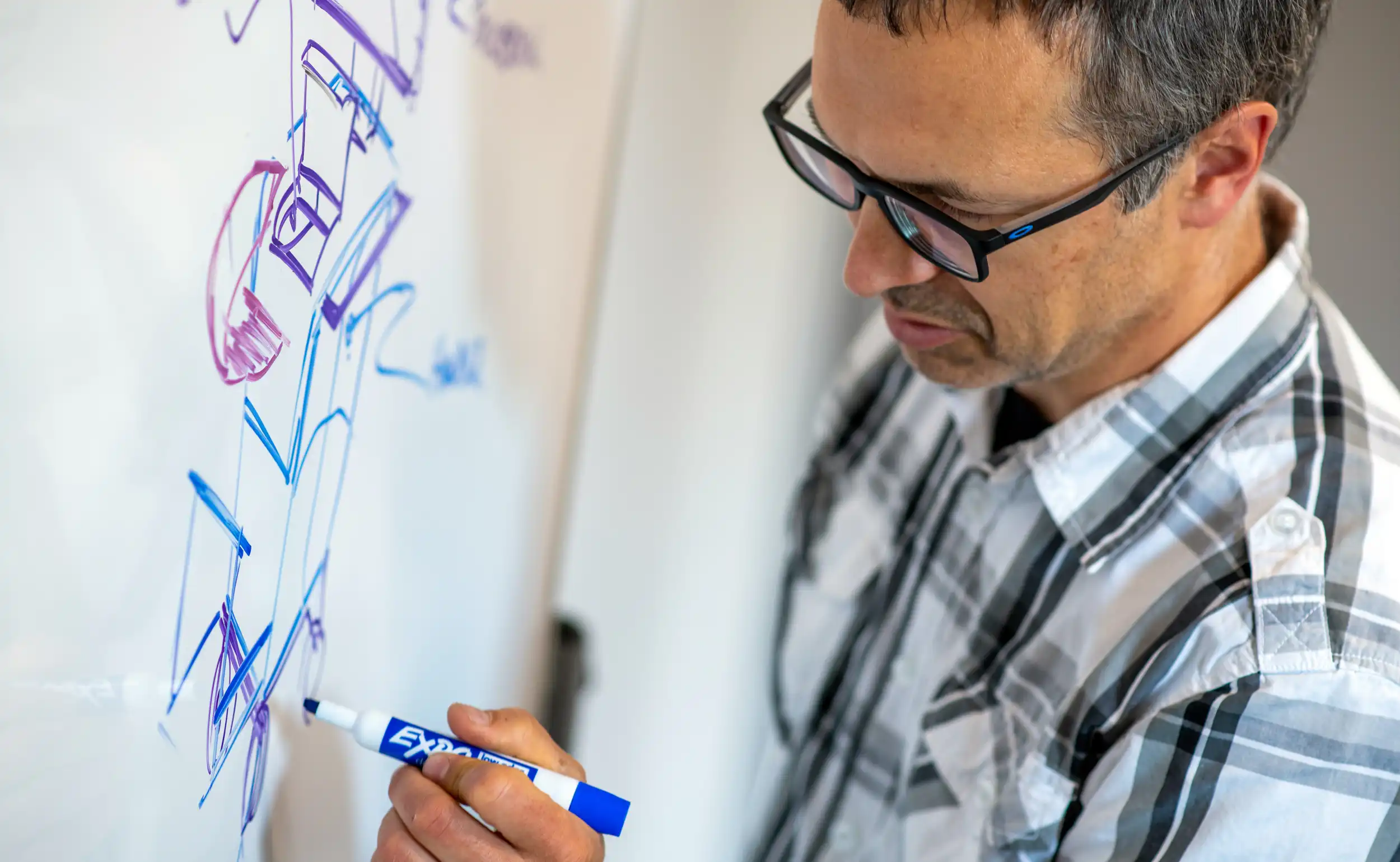 Engineer sketching medical device concept diagrams on a whiteboard.