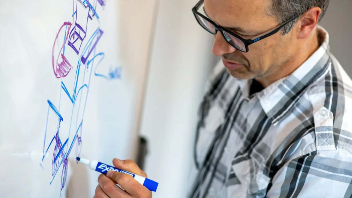 Engineer sketching early medical device concepts on a whiteboard during initial design exploration.
