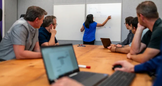 Team collaboration session in Victoria with project manager leading a whiteboard planning discussion.
