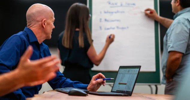 Group of professionals brainstorming around a flip chart during a project planning meeting.