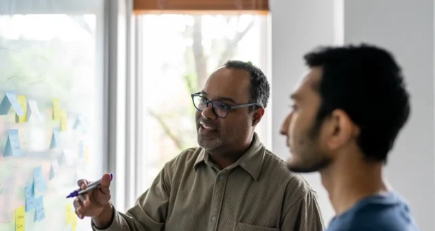 Team members collaborating at a whiteboard covered with sticky notes during a design session in Toronto.