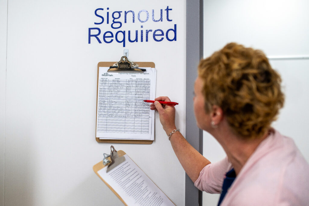 Team member signs out engineering equipment using a StarFish Medical tracking form, supporting documentation control and QMS compliance.