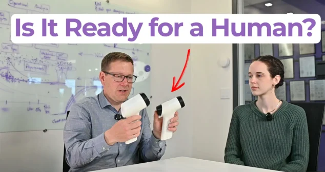 Two people seated at a table holding handheld medical device prototypes, with text overlay reading "Is It Ready for a Human?" — MedDevice by Design episode on clinical prototypes for human use