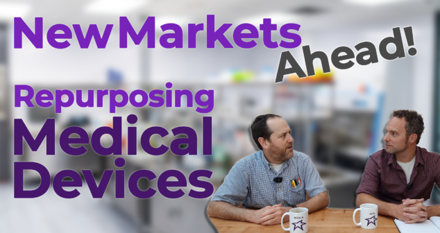 Two professionals discussing strategies for repurposing medical devices into new market sectors, sitting at a table with mugs featuring their names (Nick and Joris) and a star logo. The background is a blurred office or laboratory setting. The overlay text reads, 'New Markets Ahead! Repurposing Medical Devices,' in bold purple and black fonts, emphasizing innovation and market expansion.