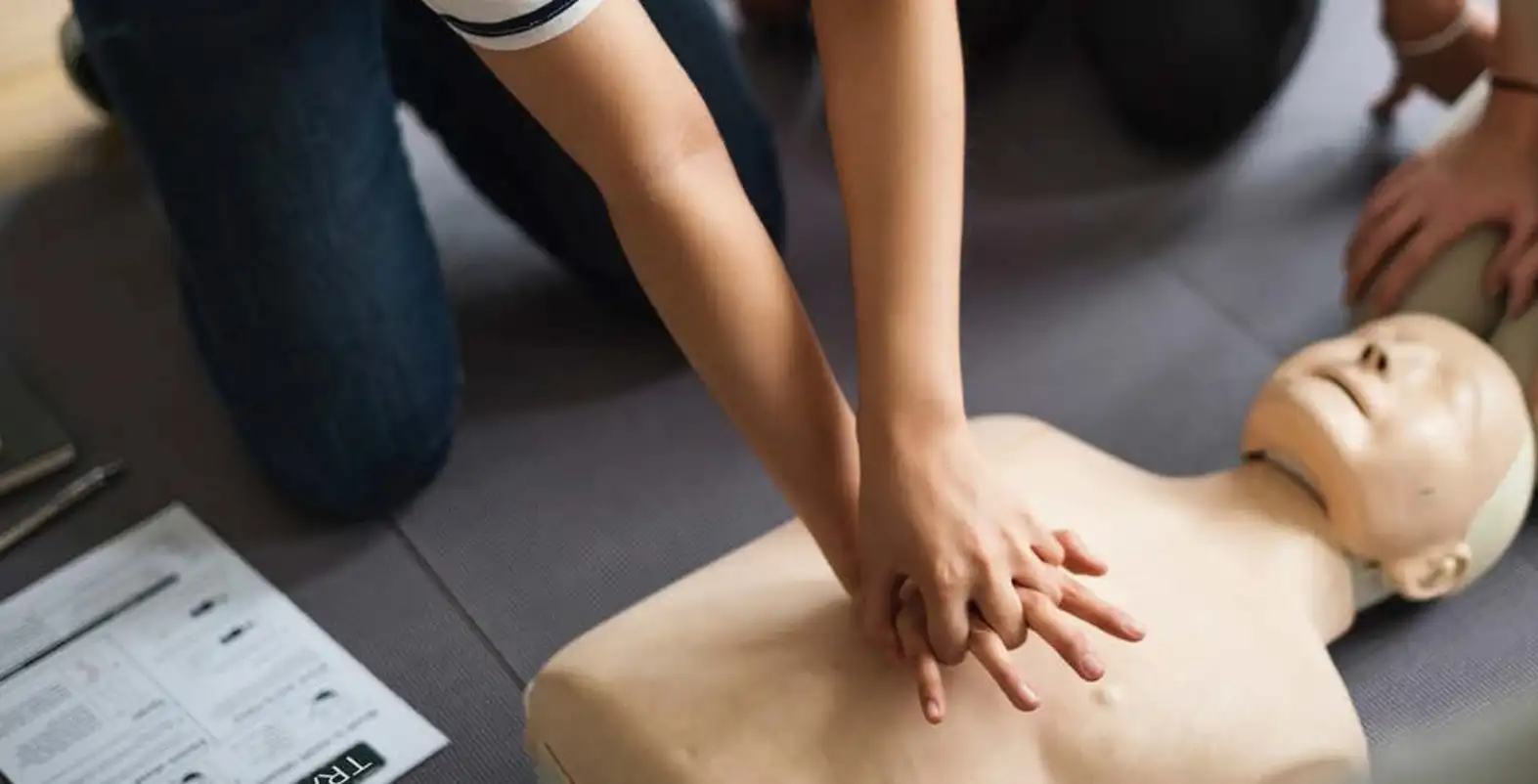 Participant performing chest compressions on a CPR mannequin during representative medical device usability training session.